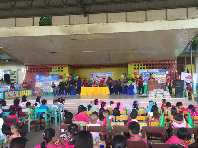 Affordable house and lot BRIAGADA ESKWELA event with kids in a court and a stage